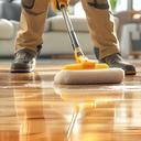 James polishing hardwood floors in a bright living room with a playlist on his phone